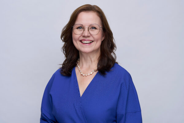 Karin Rosenberger, blaue Bluse, grauer Hintergrund